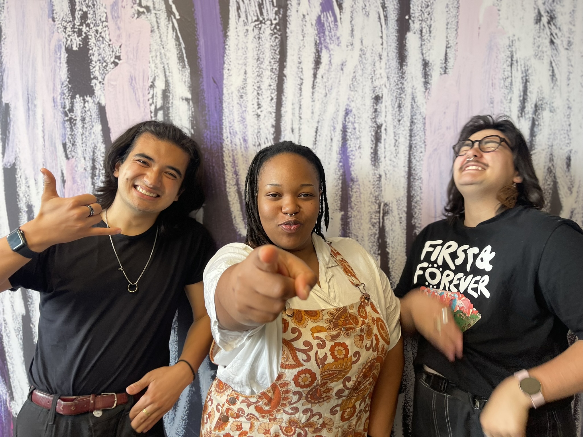 Toyo, Sibu and Moirra, our ROAR project team — two young people of colour and a young Blak person, standing against a colourful wall